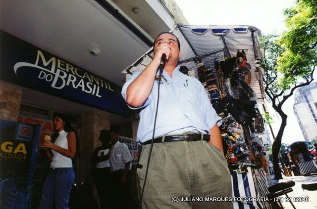 Dirigente fala ao microfone durante manifestação na rua, diante do Mercantil do Brasil.