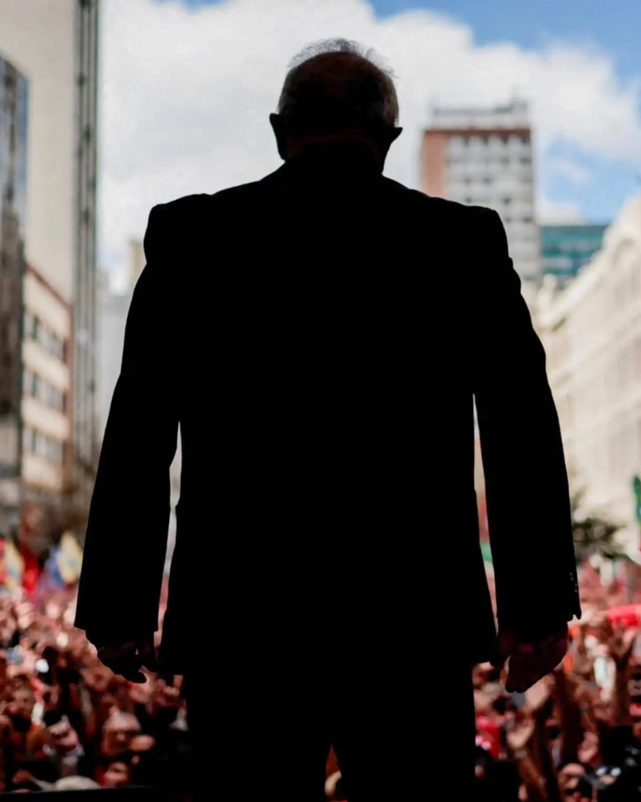 Silhueta de Lula diante de uma multidão, vista de costas.